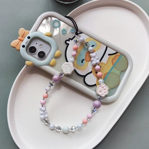 Detailed close-up of a cute resin bear and cat paw beaded phone strap on a ceramic tray