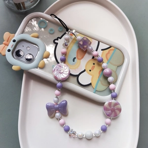 Handmade macaron candy phone strap with purple bow and star beads in a ceramic tray
