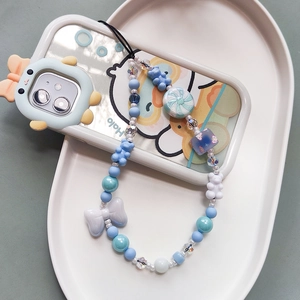 Cute beaded phone wrist strap with blue resin bows and bear charms on a white tray