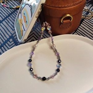 Detail of beaded phone strap with vintage purple crystals and heart charms in a tray