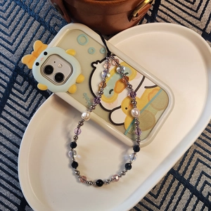 Beaded phone strap with pearls and crystals on a cartoon case over a tray