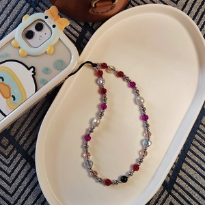 Colorful beaded phone wrist strap with crystal hearts and metallic beads on a ceramic tray