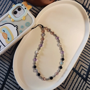 Detail of beaded phone wrist strap with purple crystals, pearls and metal spheres