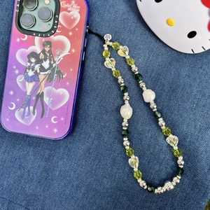 Close-up of beaded phone strap with crystal hearts and Sailor Moon case on denim