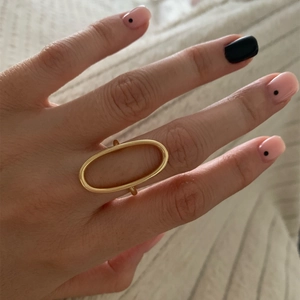 Polierter goldener Messing-Ovalring am Finger auf weichem Strickstoff-Hintergrund