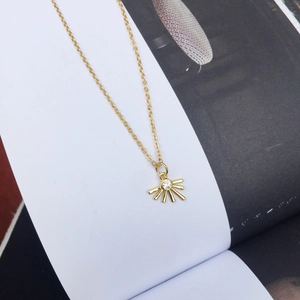 Detail of 18K gold sunburst pendant necklace with a brilliant zircon stone on a magazine