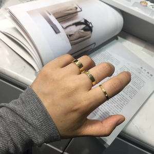 Three-piece minimalist gold polished rings shown being worn on hand over a magazine
