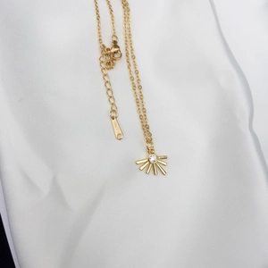 Detail of 18K gold-plated stainless steel necklace with sunburst zircon pendant on silk