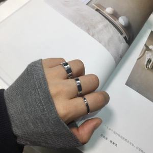 Close-up of minimalist silver rings in three widths worn as a stacking set