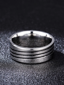 Macro detail of men's wide stainless steel ring with black grooves and brushed texture