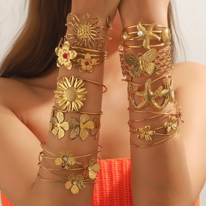 Goldenes Boho-Armreif-Set mit Sonnenblumen-, Seestern- und Korallenmotiven am Handgelenk