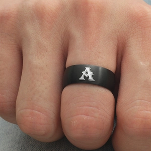 Primer plano de un anillo negro mate con la letra A gótica plateada en un dedo masculino