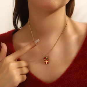 Golden satellite chain necklace with red gift box pendant on a red sweater background