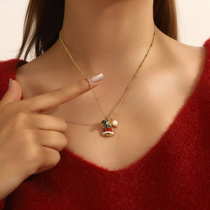 Close-up of a gold festive necklace with a red Christmas bell pendant and white pearl