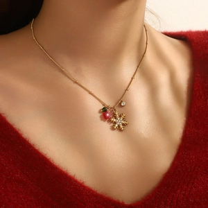 Detail of gold reindeer snowflake necklace with red flower and pearl on a red sweater