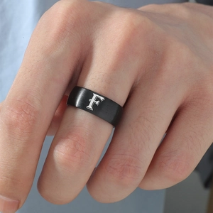 Primer plano de un anillo de acero inoxidable negro mate de 8mm con la letra F grabada