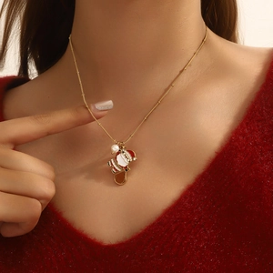Detailed close-up of a Santa Claus pendant with pearl on a gold bead chain over a red sweater