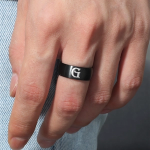 Detalle macro de anillo para hombre de 8mm en titanio negro con grabado de letra G en plata
