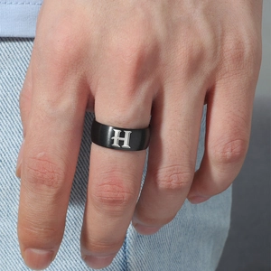 Primer plano de un anillo de acero inoxidable negro mate con la letra H grabada en blanco