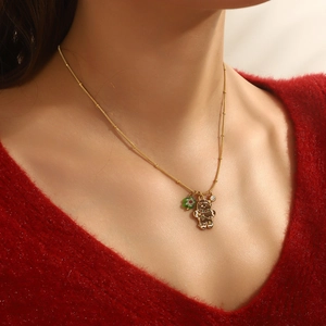 Detail of gold Christmas gingerbread man pendant necklace with enamel on a red sweater