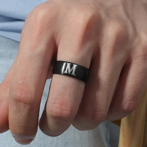 Primer plano de anillo de titanio negro con letra M grabada en la mano de un hombre