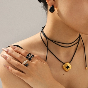Detail showing vintage black enamel earrings and matching gold necklace set on a model