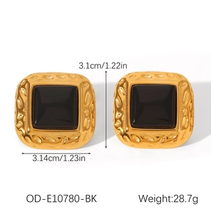 Macro view of oversized square earrings with 18k gold hammer texture and black enamel inlay
