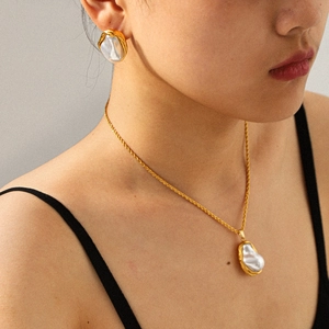 Elegante set di collana e orecchini con perle barocche dorate indossati da una modella
