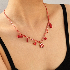 Detail of hand-woven rope necklace with multiple red enamel charms worn by a model