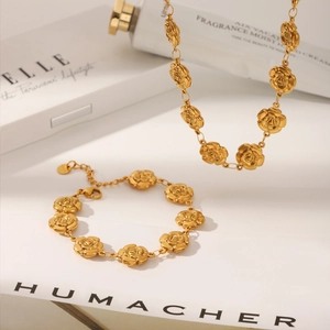 Detail of elegant gold stainless steel necklace and bracelet set with carved 3D rose flowers