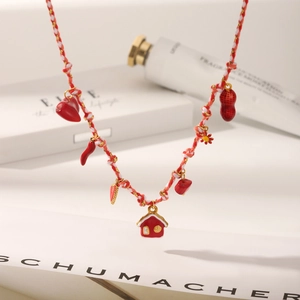 Detail view of red house and heart charms on a woven red and white rope necklace
