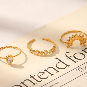 Detailed view of three gold-plated stackable rings with zircon insets on vintage paper