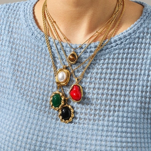 Détail de colliers dorés vintage superposés avec pendentifs en turquoise et oeil de tigre