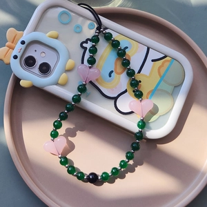 Handmade green glass beaded phone wrist strap with resin heart charms on a beige tray