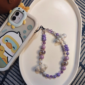 Cute purple bear beaded phone strap with white clouds and galaxy beads on a tray