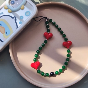 Green beaded phone strap with red resin hearts on a cartoon phone case and tray