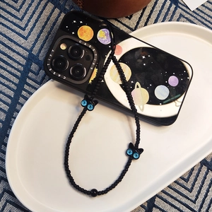 Détail de dragonne de téléphone noire perlée avec pendentifs chat et coque étoilée