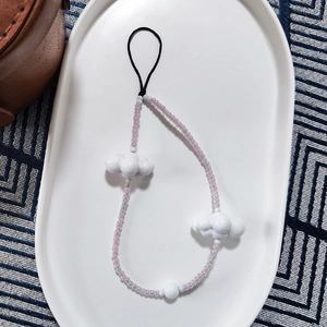 Detail of beaded phone wrist strap featuring lavender beads and white cloud charms
