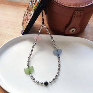 Detail of beaded phone wrist strap with colorful matte hearts and silver beads on ceramic plate