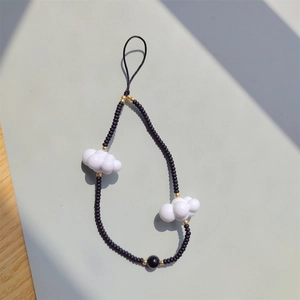 Detail of beaded phone strap featuring matte black beads and white cloud charms