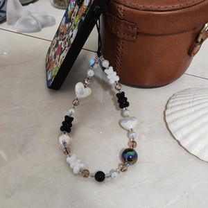 Handmade beaded phone strap with iridescent heart and bear charms on a mobile case