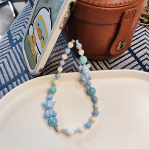 Handmade beaded phone strap featuring light blue bears and colorful round beads on white tray