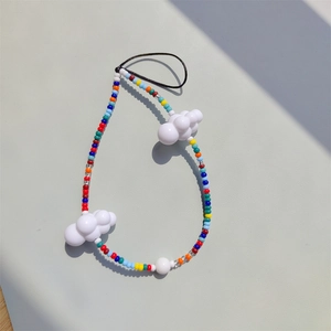 Macro detail of colorful beaded phone strap with white cloud charms on grey background