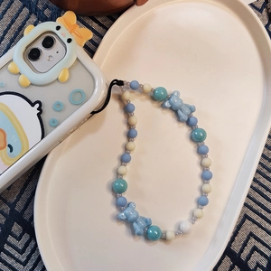 Handmade beaded phone strap with cute blue bears and colorful resin beads on white tray