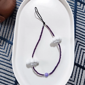 Detail view of purple beaded phone wrist strap featuring white resin cloud charms