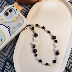 Detail of beaded phone strap with black and white beads and cute bear charms