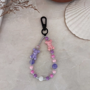 Handmade beaded keychain with purple and pink bear charms on marble background