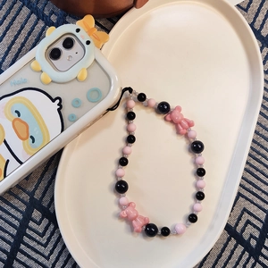 Detail of pink and black beaded phone wrist strap with cute bear beads on white plate