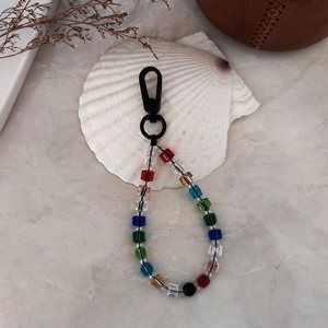 Macro detail of rainbow beaded keychain with acrylic cubes and matte lobster clasp on marble