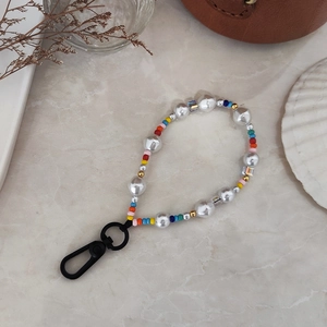Handmade rainbow bead and baroque pearl keychain with black carabiner on marble background